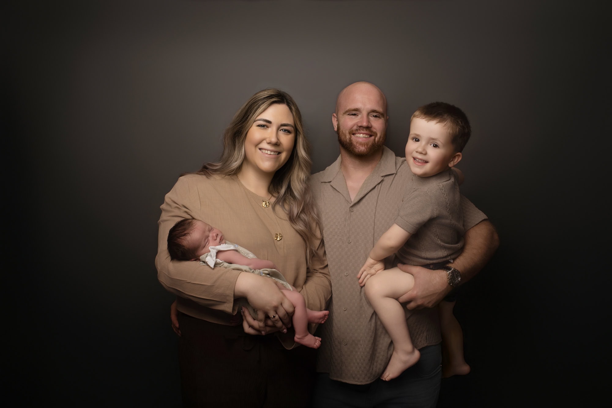 Family of four with newborn baby and toddler wearing neutral colours in an Ashbourne studio