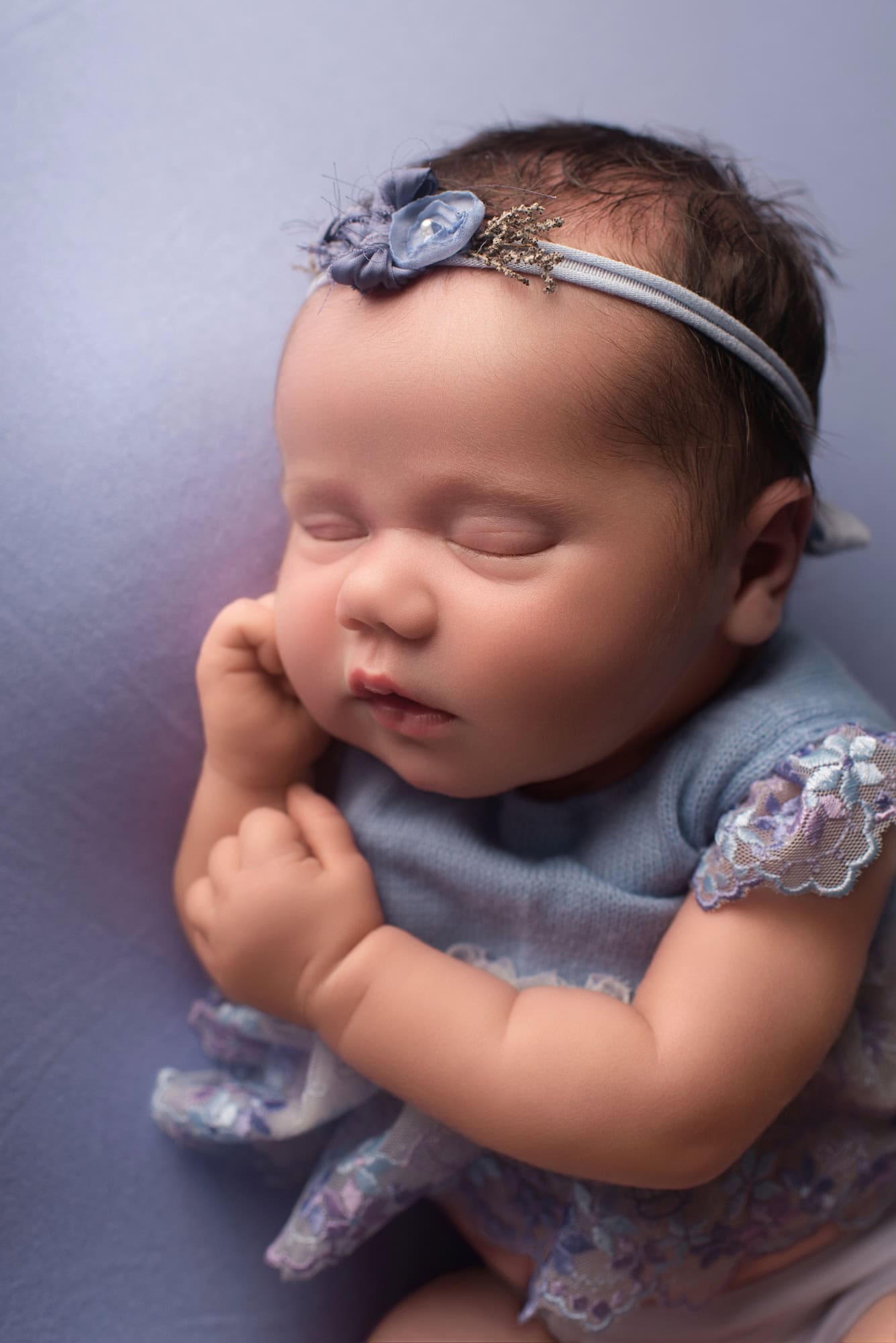 Sleeping newborn baby in a blue lace romper at an air-conditioned newborn studio near Ashbourne