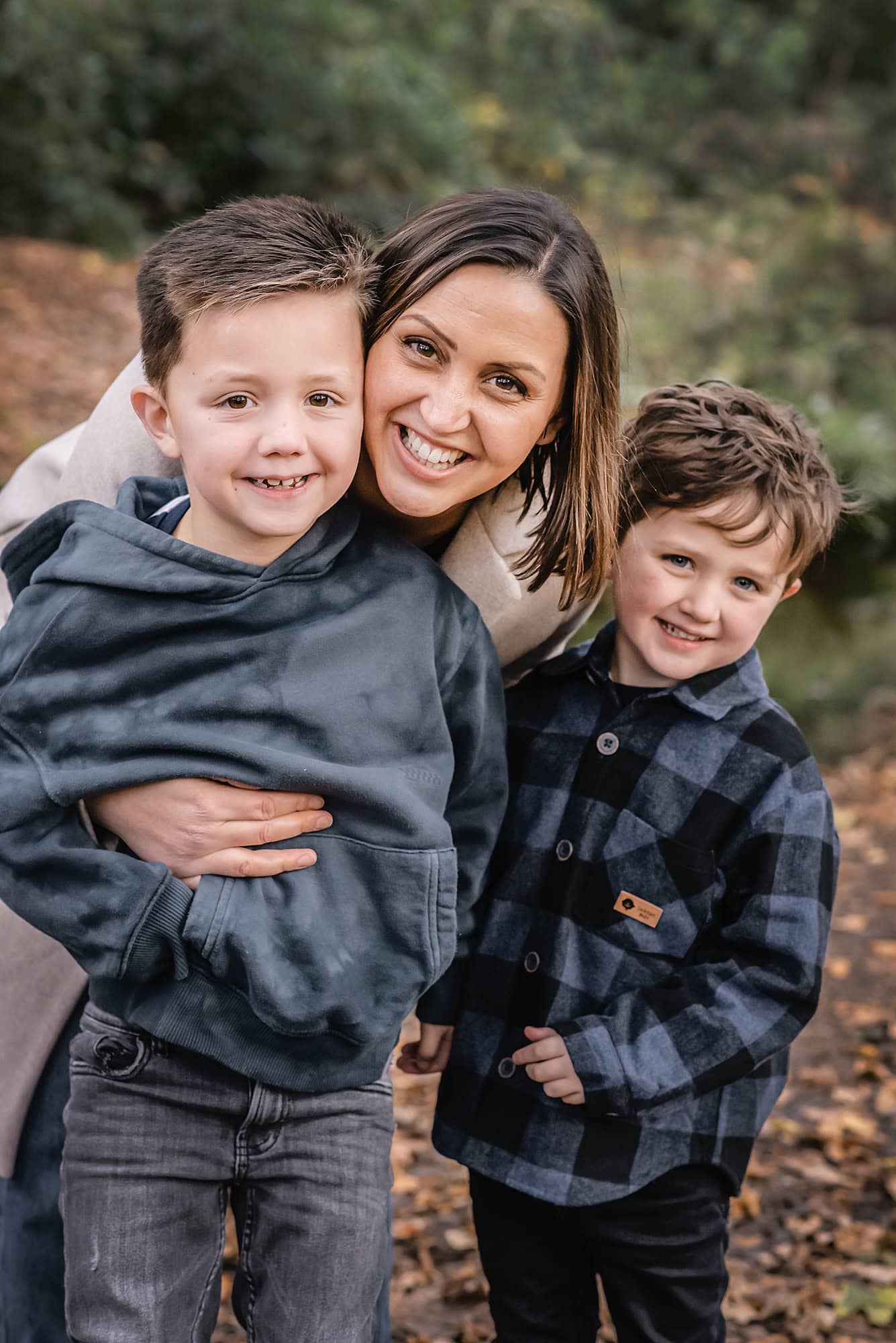 Mum smiling cheek to cheek with her two sons during an autumn family photo session